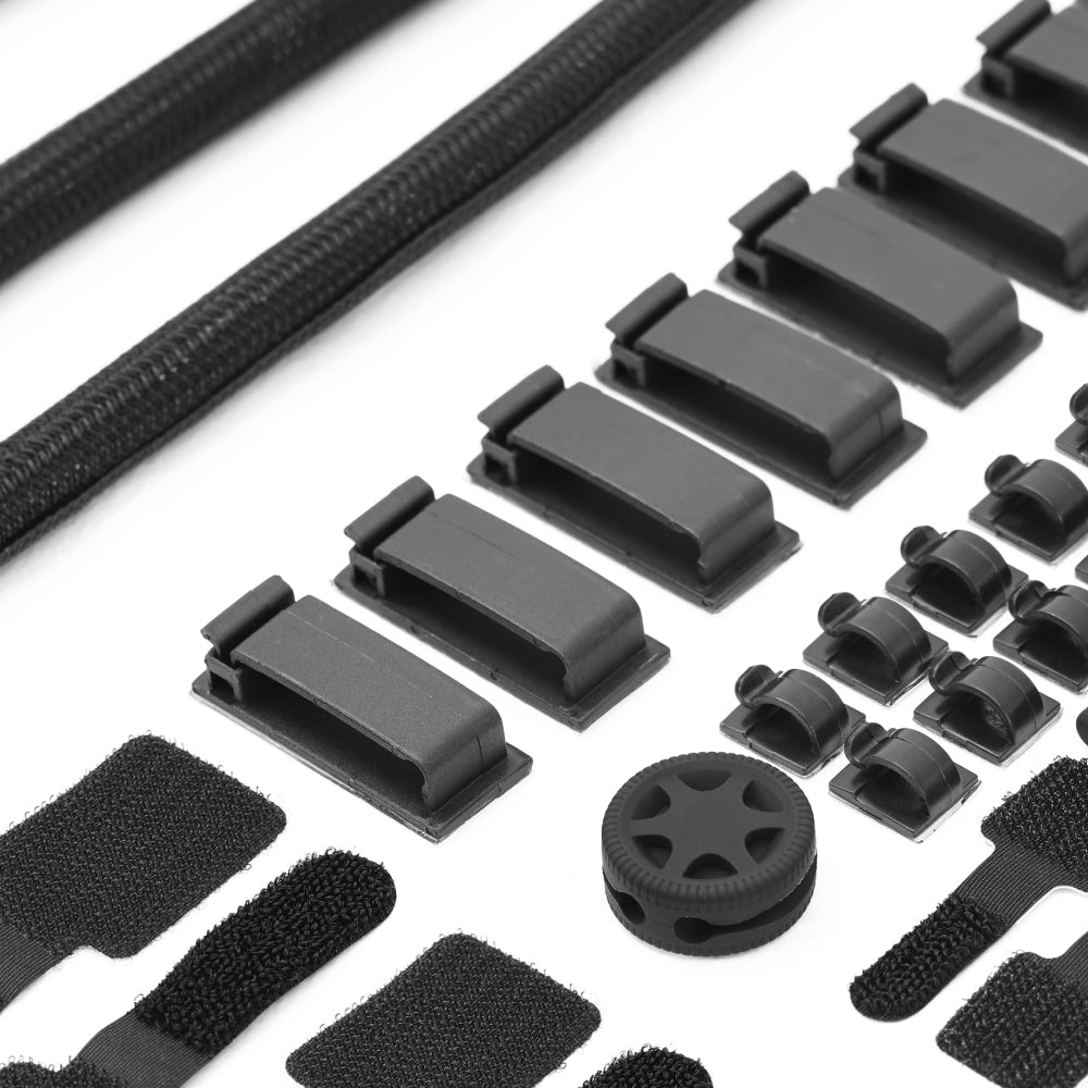 Black plastic tools and parts for cable management, featuring clips, sleeves, Velcro straps, and an organizer wheel.