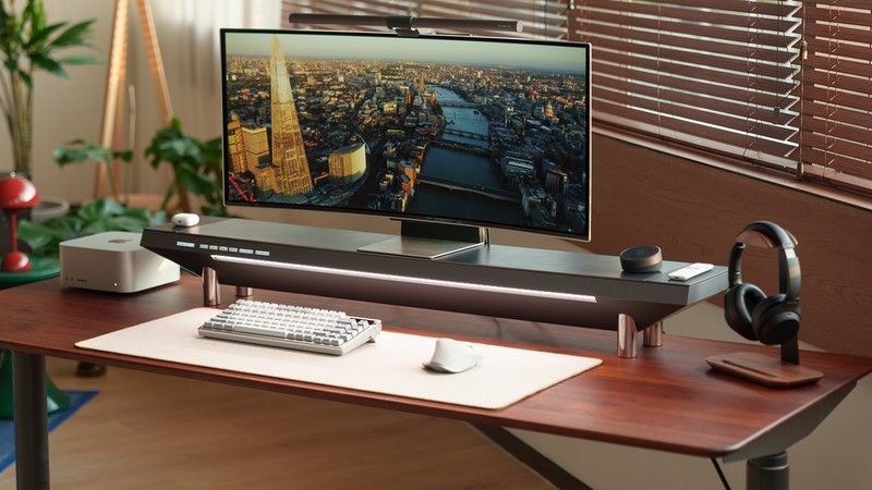 A modern, minimalist home office desk setup with a dark wood tabletop, an ultrawide monitor on a raised stand——Hexcal Studio™, and warm ambient lighting.