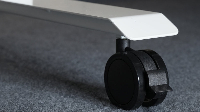 Locking caster fitted to a white standing desk foot