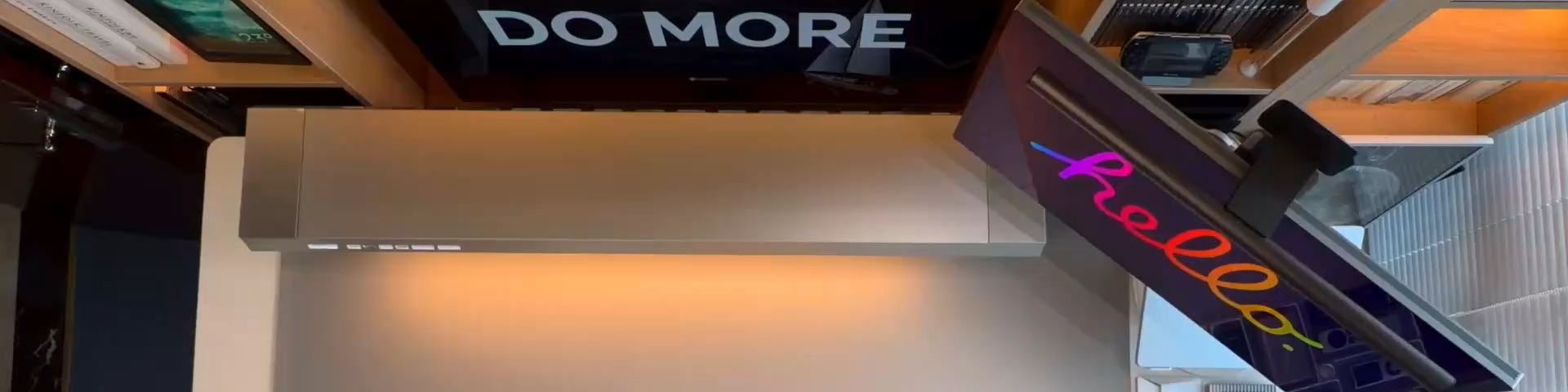 Modern office desk with computer setup, illuminated signs, and a motivational quote.